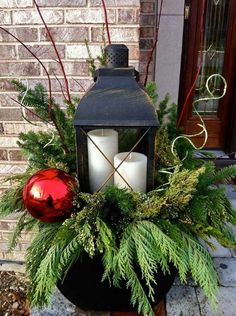 a candle holder with candles and greenery in front of a brick building