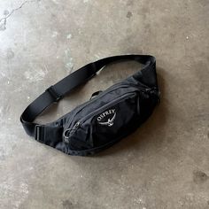 a black fanny bag sitting on top of a cement floor