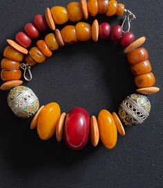 Moroccan Tagmoute Berber enameled eggs with large African Amber beads handmade chunky nomad necklace. Beautiful big and chunky handmade vintage beaded Moroccan Tagmoute enameled vintage eggs Measuring approximately 1.5 inches in length by 1.5 inches in height. 2 Enameled eggs with green, blue and Wooden Beads Amulet Jewelry For Festival, Amulet Style Jewelry With Wooden Beads For Festival, Festival Amulet Style Jewelry With Wooden Beads, Handmade Artisan Round Beads, Bohemian Orange Hand-strung Necklace, Artisan Necklace With Round Beads For Festivals, Festival Amulet Jewelry With Wooden Beads, Traditional Orange Beads For Crafting, Orange Wooden Beads Jewelry For Festival