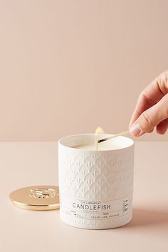 a person is holding a spoon in a white candle holder next to a gold coin