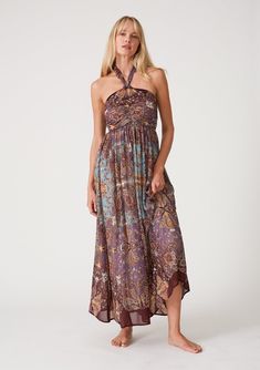 [Color: Raisin/Teal] A front facing image of a blonde model wearing a bohemian halter maxi dress in a multi colored purple and teal floral print. With a tie neckline Bohemian Chiffon Halter Neck Dress, Flowy Boho Print Halter Neck Dress, Flowy Halter Neck Dress With Boho Print, Paisley Print Maxi Dress For Beach, Brown Halter Neck Maxi Sundress, Brown Halter Neck Sundress Maxi Dress, Brown Paisley Print Summer Dress, Purple Printed Maxi Dress, Beach Paisley Print Maxi Dress