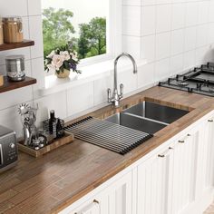 a kitchen counter with a sink and stove top in front of a window overlooking the trees