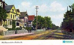 an old postcard shows houses on the side of a road in front of a fence