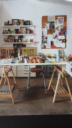 an art studio with two desks and shelves on the wall, filled with various items