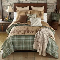 a bedroom with stone walls and wood flooring, made up in plaid bedding