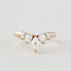 a three stone ring with four pear shaped diamonds on the band, set in yellow gold