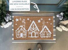 a door mat with houses drawn on it next to some christmas decorations and trees in the background