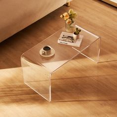 a clear coffee table with a flower vase on top