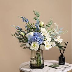 a vase filled with blue and white flowers sitting on top of a marble topped table