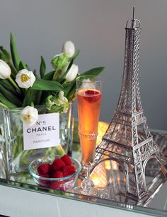 the eiffel tower is next to a glass of wine and raspberries