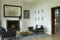 a living room filled with furniture and a fire place under a mirror on the wall