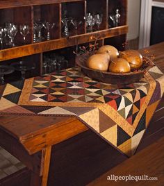 a bowl of onions sitting on top of a wooden table next to a wine glass rack