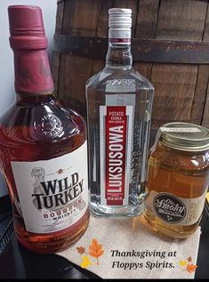 two bottles of wild turkey bourbon next to a barrel