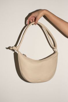 A soft form crescent shaped bag in vegetable tanned semi-aniline cowhide, 100% leather. Shown here with the strap doubled, but can be lengthened. 11" wide, 7" tall at center, 2" deep with a 40" total strap length. Zip closure. Leather Baguette Bag With Smooth Grain For Daily Use, Everyday Leather Baguette Bag With Smooth Grain, Versatile Leather Baguette Bag With Leather Handles, Leather Shoulder Bag With Round Handle For On-the-go, Leather Baguette Bag With Round Handle For Everyday, Beige Soft Leather Baguette Bag, Soft Leather Shoulder Bag With Round Handle, Daily Use Soft Leather Shoulder Bag With Round Handle, Round Handle Soft Leather Shoulder Bag For Daily Use