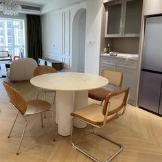 a dining room table with chairs and a refrigerator in the backgroung area