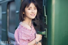 a young woman is leaning against a green door