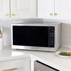 a microwave oven sitting on top of a kitchen counter next to a plate of food