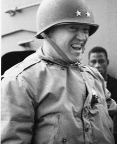 black and white photograph of a man wearing a helmet with stars on it, standing next to another man