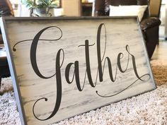 a wooden sign that says gather on the floor in front of a couch and chair