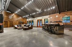 a large open living room with lots of furniture and exposed ceiling lights above the bar