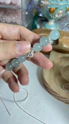 a person is holding some beads in their hand and they are sitting on a table