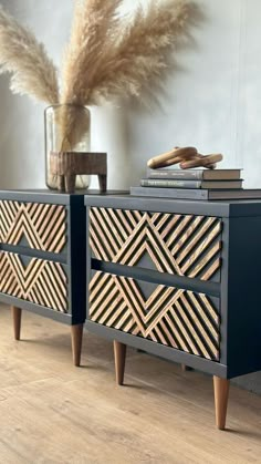 a black and gold dresser sitting on top of a wooden floor next to a plant