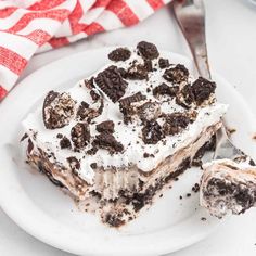 a piece of oreo cake on a white plate with a fork and red checkered napkin