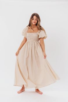 Be the life of the party in the Nan Maxi Dress! This beautiful gown comes in a gorgeous, multi-season neutral hue, and features a smocked bodice and puffed sleeves that can be worn on or off the shoulder - it's like getting two dresses in one! Style the Nan with slides for a casual, feminine outfit, or with neutral heels for the perfect event dress. FIT: Runs true to size. MATERIAL: GARMENT DETAILS: Neutral maxi dress with empire waist silhouette, smocked bodice, and puffed sleeves with elastica Puff Sleeve Midi Dress For Garden Party, Puff Sleeve Dress With Smocked Back For Garden Party, Garden Party Puff Sleeve Dress With Smocked Back, Spring Puff Sleeve Dress For Gatherings, Flowy Smocked Bodice Puff Sleeve Dresses, Prairie Dress With Puff Sleeves For Garden Party, Elegant Dress With Smocked Back And Bishop Sleeves, Puff Sleeve Ruched Maxi Dress For Garden Party, Flowy Ruched Puff Sleeve Dress For Garden Party