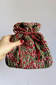 a hand holding a knitted bag with red, green and white stripes on it