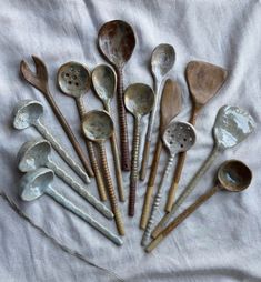 an assortment of old metal spoons on a white cloth