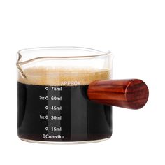 a glass filled with liquid next to a wooden handle