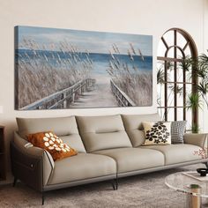 a living room filled with furniture and a painting on the wall above it's windows