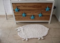 a crocheted sheep rug on the floor next to a dresser with blue stars