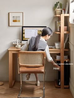 a woman sitting at a desk with her back to the camera and looking at a computer screen