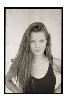 black and white photograph of a young woman with long hair wearing a tank top posing for the camera