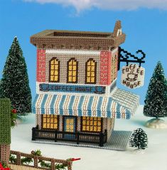 a small building made out of legos in the snow with christmas decorations around it