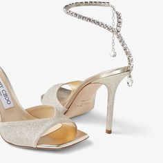 a pair of high heeled shoes with chains hanging from the ankle and heels in gold glitter