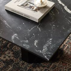 a black marble coffee table with a book on top