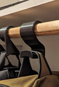 the back end of a backpack hanging on a wall next to a wooden pole with two black handles