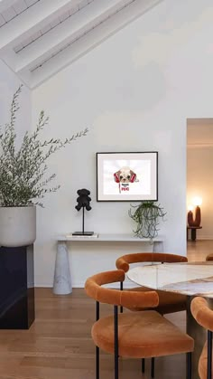 the dining room table is surrounded by chairs and a vase with a plant in it