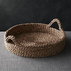 a woven basket sitting on top of a gray tablecloth covered floor next to a black wall