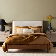 a bedroom with a bed, nightstands and two vases on the side tables