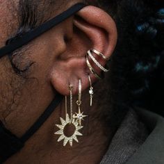 a close up of a person's ear wearing gold earrings and hoops with diamond accents