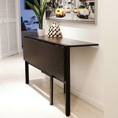 a black and white vase sitting on top of a wooden table next to a painting