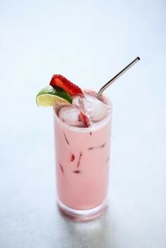 a pink drink with strawberries and lime on the rim