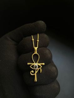 This elegant necklace features a stunning pendant combining two of the most iconic symbols of ancient Egypt: the Ankh and the Eye of Horus. Crafted from high-quality sterling silver, the pendant showcases an intricate design that includes the Eye of Horus set within the loop of the Ankh. The necklace is complemented by a delicate chain adorned with small, evenly spaced beads, adding a touch of sophistication to this unique piece. Perfect for anyone interested in Egyptian mythology or looking for Ankh Necklace, Iconic Symbols, Real Gold Jewelry, Egyptian Mythology, Jewelry Workshop, Eye Of Horus, Elegant Necklace, Delicate Chain, Elegant Necklaces