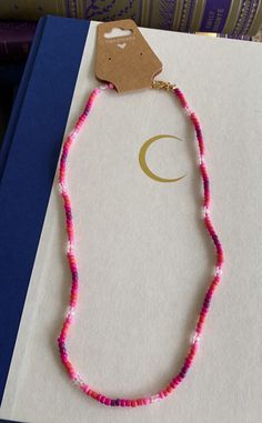 a pink beaded necklace sitting on top of a book