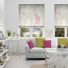 a living room filled with furniture and windows covered in roman blind shades on top of them