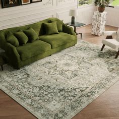 a green couch sitting on top of a wooden floor next to a chair and table