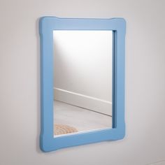 there is a mirror on the wall with a blue frame around it and a white floor